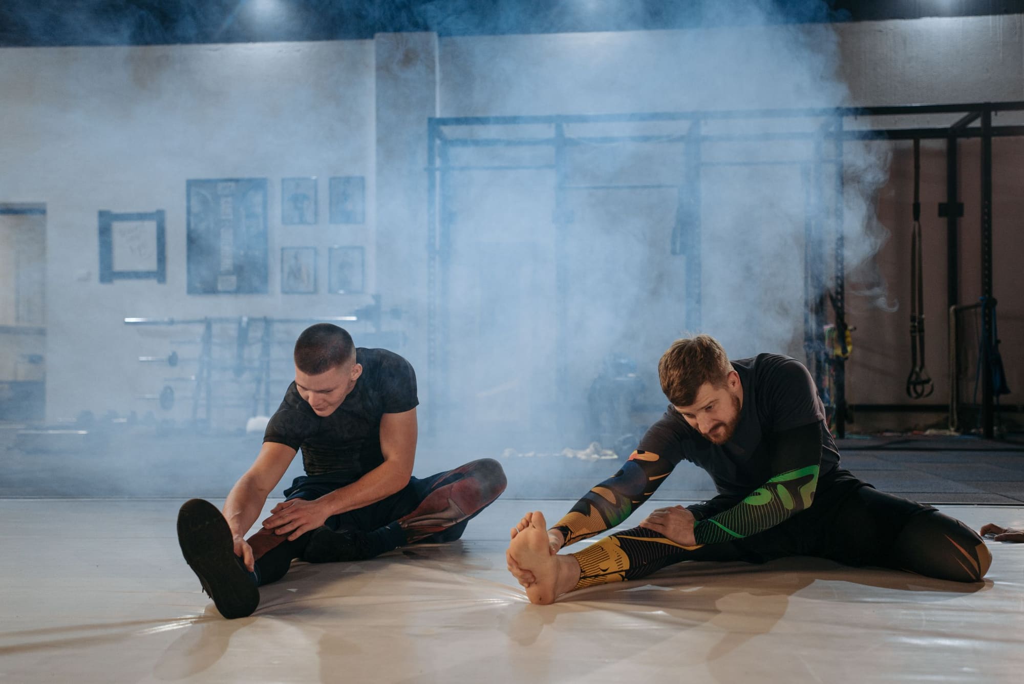 Athletes stretching on a mist-lit gym floor before training